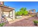 Expansive backyard with covered patio, outdoor furniture, mature tree, BBQ and decorative rock at 1213 High Altitude Ave, North Las Vegas, NV 89032