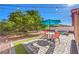 Landscaped backyard with outdoor furniture, teal umbrella, pavers and decorative rock under string lights at 1213 High Altitude Ave, North Las Vegas, NV 89032
