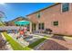 Backyard patio with outdoor furniture, a teal umbrella, green turf and string lights at 1213 High Altitude Ave, North Las Vegas, NV 89032