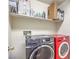 Laundry room featuring a gray front load washer and red dryer with a shelf above filled with supplies at 1213 High Altitude Ave, North Las Vegas, NV 89032