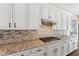 Kitchen with white cabinets, granite counters, stainless steel range and mosaic backsplash at 12168 Dorada Coast Ave, Las Vegas, NV 89138