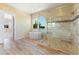 This bathroom features wood-look tile floors, a soaking tub, and a large glass enclosed shower with bench seating at 12168 Dorada Coast Ave, Las Vegas, NV 89138