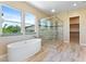 This main bathroom features wood-look tile floors, a soaking tub, and a glass enclosed shower at 12168 Dorada Coast Ave, Las Vegas, NV 89138