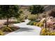 A curved walking path through natural desert landscaping with trees, shrubs, and yellow flowers at 1467 Melodic Lark Ln, Las Vegas, NV 89138