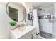 Bathroom with a white vanity, round mirror, modern lighting, and a shower with marble-style tiling at 147 Cervantes St, Las Vegas, NV 89101