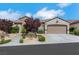 View of the house's exterior and driveway featuring lovely landscaping, mature shade trees, and a two car garage at 2244 Shadow Canyon Dr, Henderson, NV 89044