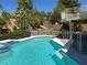 Inviting in-ground pool and spa with serene landscaping, a secure mesh fence, and a cozy seating area at 2817 Whispering Wind Dr, Las Vegas, NV 89117