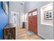 Bright foyer featuring hardwood floors, an orange door, a high ceiling, and artwork decorating the entrance to the home at 2822 Ashby Ave, Las Vegas, NV 89102