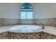 Close-up of soaking tub with tile surround, modern faucet and natural light from the window at 3633 Fox Heather Dr, Las Vegas, NV 89129
