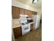 Compact kitchen with white appliances, wood cabinets, and tiled floors, providing essential functionality at 4820 Mahogany Dr, Las Vegas, NV 89110