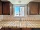 Close-up of the kitchen sink featuring neutral tile countertops, wooden cabinets and a view from the window at 5460 Conville Pl, Las Vegas, NV 89120