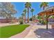 Lush backyard featuring artificial turf, mature trees, stone pavers, a rock waterfall, and a covered patio at 6224 Red Pine Ct, Las Vegas, NV 89130