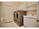 Laundry room with washer, dryer, utility sink, cabinets, and a tile floor at 66 Sunset Bay St, Las Vegas, NV 89148