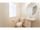 This half bathroom has a window, toilet, sink with pedestal, and wood floors at 6821 Treble Clef Ave, Las Vegas, NV 89139