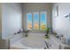 Bright bathroom featuring a soaking tub with plants near a set of three sunny windows at 6837 Dragonfly Rock St, Las Vegas, NV 89148