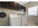 Functional laundry room equipped with a washer, dryer, and overhead cabinets for storage at 6837 Dragonfly Rock St, Las Vegas, NV 89148
