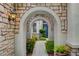 Stone walkway leads through arched entrances to a charming blue front door framed by lush greenery at 729 Sir James Bridge Way, Las Vegas, NV 89145