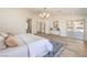Bright main bedroom boasts wood floors, modern chandelier, ensuite bathroom, and sliding glass doors to the outdoor space at 7410 Bridlehorne Ave, Las Vegas, NV 89131