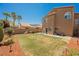 Spacious backyard with a combination of grass, landscaping, and a view of the home's exterior at 7690 Morning Lake Dr, Las Vegas, NV 89131