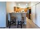 Well-lit kitchen featuring oak cabinetry, stainless steel refrigerator, breakfast bar, and neutral tile flooring at 10336 Birch Bluff Ln, Las Vegas, NV 89145