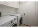Bright laundry area with front load washer and dryer and ample upper cabinet storage at 10336 Birch Bluff Ln, Las Vegas, NV 89145