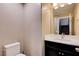 A half bathroom features a modern vanity with a light countertop and dark cabinet below a large framed mirror at 10512 Mann St, Las Vegas, NV 89141