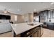 A contemporary kitchen island with white countertops, dark cabinets, and stainless steel appliances in an open-concept living space at 10512 Mann St, Las Vegas, NV 89141
