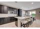 Modern kitchen with dark cabinets, stainless steel appliances, and an island with bar seating at 10512 Mann St, Las Vegas, NV 89141
