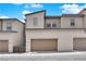 New townhome with neutral colored stucco and a two-car garage with a brick paver driveway at 11407 Ethereal Landing Ave, Las Vegas, NV 89138