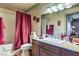 Well-lit bathroom boasts granite countertops and a shower-tub combination with a red shower curtain at 1150 N Buffalo Dr # 1022, Las Vegas, NV 89128
