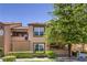Two-story condo featuring desert landscaping with a mix of green bushes and a tall tree at 1150 N Buffalo Dr # 1022, Las Vegas, NV 89128