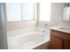 Bright bathroom featuring a tub, modern fixtures, and a corner window at 1405 Gilbert Creek Ave, North Las Vegas, NV 89031