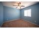 Stylish blue bedroom featuring carpet floors, a ceiling fan, and a window for natural light at 1405 Gilbert Creek Ave, North Las Vegas, NV 89031