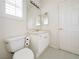 Clean white bathroom featuring a toilet, sink, and mirrored vanity with window shutters at 2451 Tour Edition Dr, Henderson, NV 89074