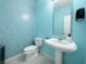 Powder room featuring stylish blue tiled wall, pedestal sink and modern fixtures at 2451 Tour Edition Dr, Henderson, NV 89074