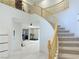 Grand foyer showcasing a curved staircase with wooden railings and open-concept layout to the living spaces at 2451 Tour Edition Dr, Henderson, NV 89074