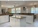 Bright kitchen featuring white cabinets, granite countertops, an island, and views to the backyard at 2451 Tour Edition Dr, Henderson, NV 89074