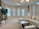 Bright living room with large windows, white sectional sofa, and modern lighting fixtures at 2451 Tour Edition Dr, Henderson, NV 89074