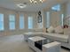 Bright living room with large windows, white sectional sofa, and modern lighting fixtures at 2451 Tour Edition Dr, Henderson, NV 89074