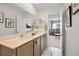 Bathroom featuring double sinks, large mirror, and a view into the living room at 329 Brockbank Pl, Henderson, NV 89011