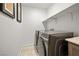 Well-lit laundry room with gray front load washer and dryer and overhead shelving at 329 Brockbank Pl, Henderson, NV 89011
