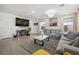 Bright living room featuring two gray sofas, wood-look tile flooring, and a modern chandelier at 329 Brockbank Pl, Henderson, NV 89011