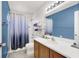 Well lit bathroom with blue accent walls, a wood vanity, and shower with a blue ombre shower curtain at 3389 Commendation Dr, Las Vegas, NV 89117