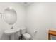 Neutral-toned half bathroom featuring a pedestal sink, toilet, and decorative round mirror at 3518 Herodain Ave, Las Vegas, NV 89106