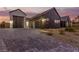 Stunning home exterior featuring a long paved driveway and multiple garage doors against a vibrant sunset at 5725 El Royale Ct, Las Vegas, NV 89149