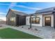 Modern home entrance featuring a covered patio, dark accents, desert landscaping, and manicured lawn at 5725 El Royale Ct, Las Vegas, NV 89149