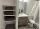 Bathroom showcasing gray vanity, framed mirror, toilet, and organized shelving unit for storage at 7885 W Flamingo Rd # 2019, Las Vegas, NV 89147