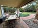 Covered patio with dining table and chairs overlooking a beautifully landscaped backyard with putting green at 8138 Yucca Springs Dr, Las Vegas, NV 89129