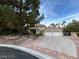 Inviting home exterior featuring a spacious driveway, three-car garage, and mature trees offering shade and curb appeal at 8138 Yucca Springs Dr, Las Vegas, NV 89129