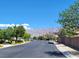 A quiet streetscape showcases the community's charm, framed by lush trees and distant mountain views at 8247 Oasis Bloom St, North Las Vegas, NV 89085